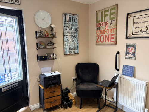The therapy room's own external door, with an armchair and shelves alongside it